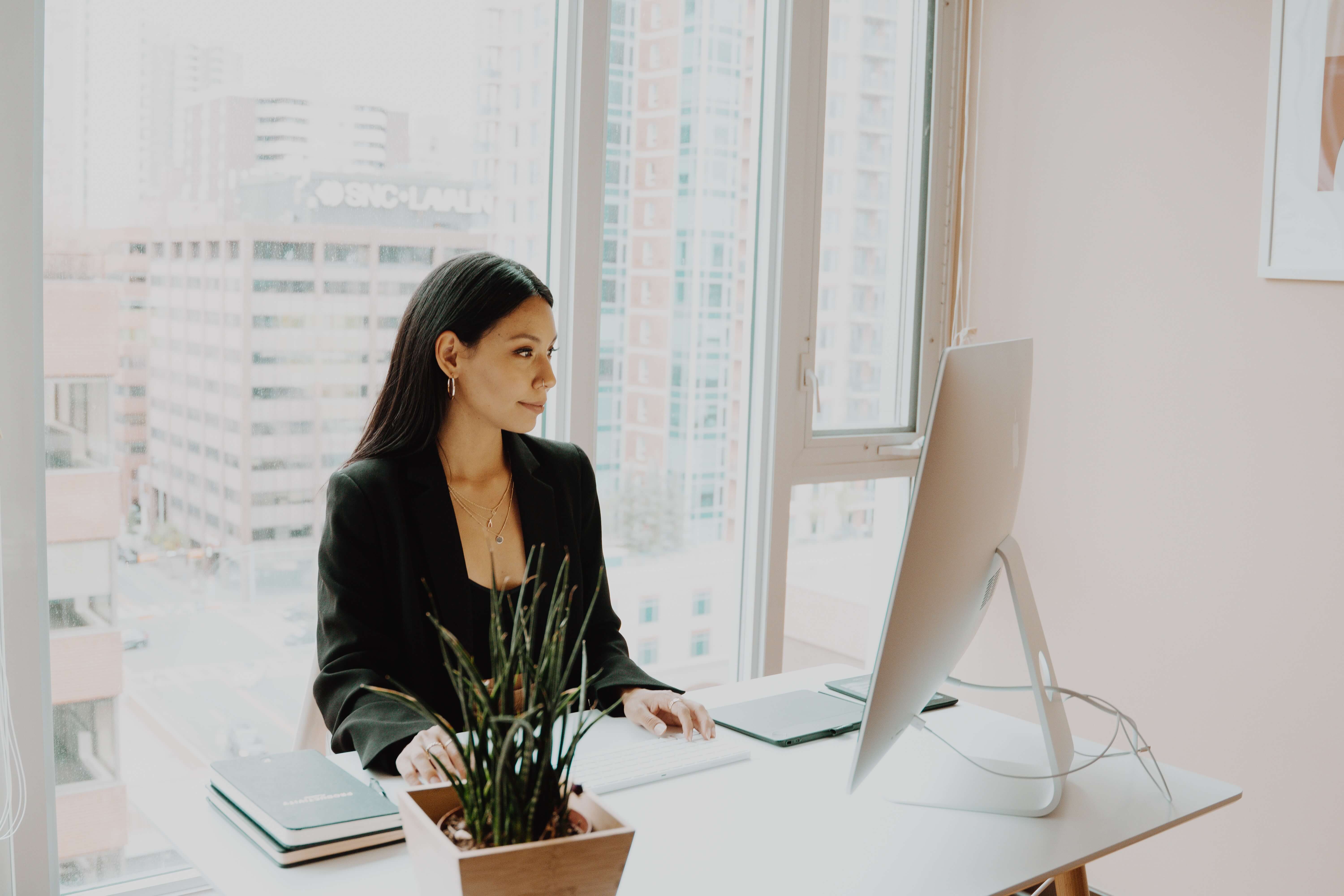 Woman working on her computer, in an office, at her desk